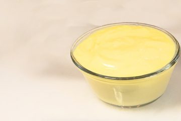 A silky serving of Delicious Classic Vailla Pastry Cream in 10 Min. sits in a cool glass ramekin atop a marble board. Simple and oh, so delicious!