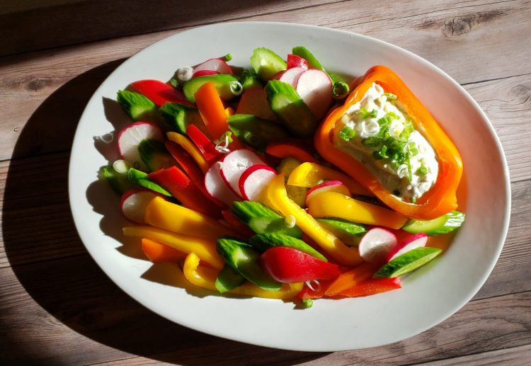 Easy Yogurt and Goat Cheese Dip. A tray of fresh summer vegetables surround a bell pepper that has been filled with this delicious dip.