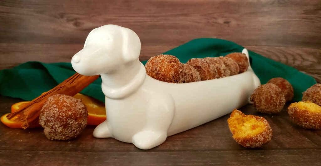 A white porcelain dish shaped like a Dachshund do proudly displays a row of Tempting 2-Bite Sweet Potato Drop Doughnuts.