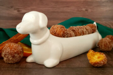 A white porcelain dish shaped like a Dachshund do proudly displays a row of Tempting 2-Bite Sweet Potato Drop Doughnuts.