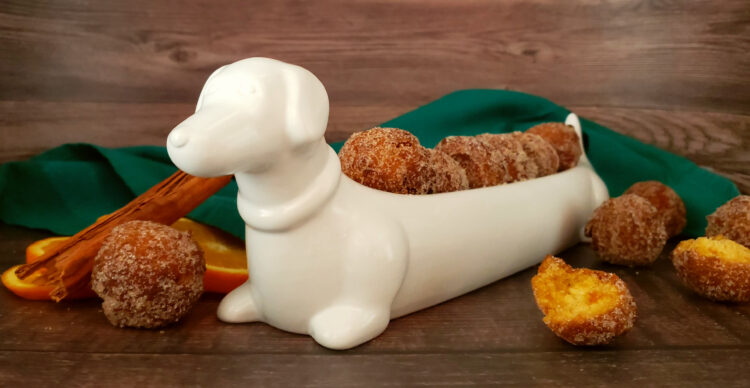 A white porcelain dish shaped like a Dachshund do proudly displays a row of Tempting 2-Bite Sweet Potato Drop Doughnuts.