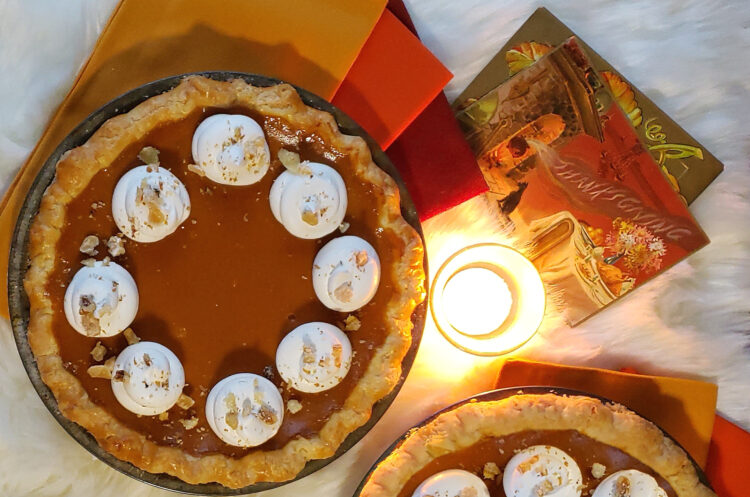 Two Easy Ginger Citrus Pumpkin Pie sit on a candle lit table awaiting the time for dessert to be served.