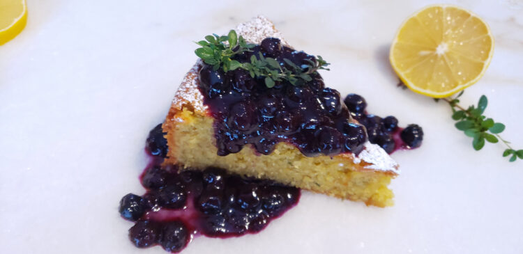 A slice of cake is topped with a generous helping of 20-Minute Thyme Infused Blueberry Sauce.