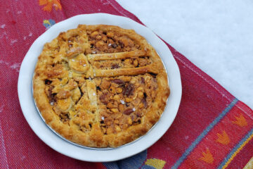 A beautiful Perfect Salted Mixed Nut Pie sits atop a snow covered table. The sea salt flakes appear like snow themselves.