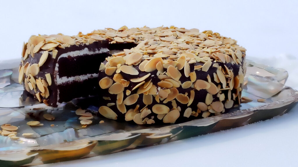A beautiful serving tray sits in the center of a pristine blanket of freshly fallen snow. Against the cool, crisp color of the while snow, sits this Decadent Chocolate Gateau Nicole. The richness of the chocolate cake layers, almond buttercream and chocolate ganache finished with toasted almond slices is stunning.