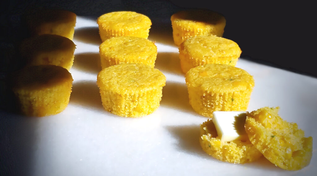 The sun illuminates a tray of Gluten Free Jalapeno Cheddar Corn Muffins as they are cooling.