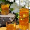 A tall pitcher of 3-Step Bless Your Heart Sweet Tea and two glasses at the ready catch the sunlight on a warm summer day. A clematis at the peak of its blooming season provides the backdrop for this beautiful, golden like sunshine beverage.
