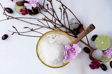 Easy 4-Ingredient Lychee Coconut Sorbet. A frosty bowl of lychee coconut sorbet sits nestled among lychee twigs, peeled lychee fruit, lime slices and fresh flowers.