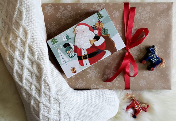 Festive wrapped presents and toys sit upon a plush white fur rug - items found at a local store by implementing Maria's 2 Ways to Slay Your Holiday Gift List Early.