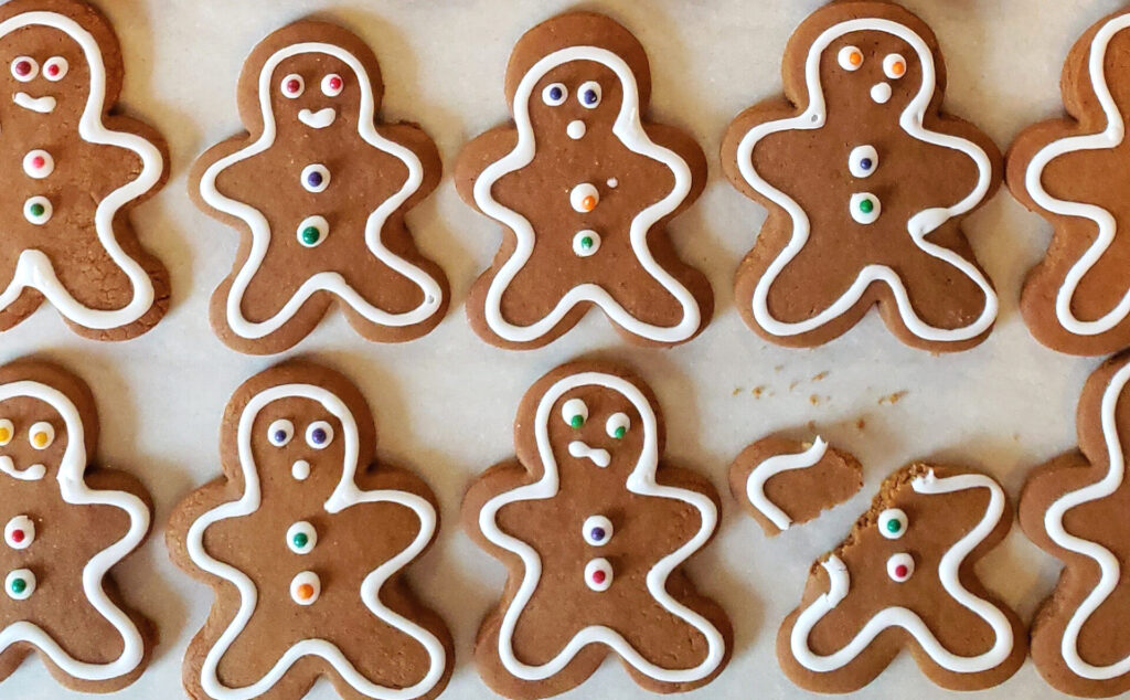 A lineup of gingerbread men with concerned faces all looking at one little gingerbread man with a broken arm. Stan recommends avoiding the holiday door buster sales and instead use these 2 Ways to Slay Your Holiday Gift List Early.