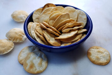 A bowl of these 4-Ingredient Easy Rustic Table Water Crackers are the only thing sitting in the middle of an empty charcuterie board - as if waiting for your suggestions as to which wine and cheese to pair with them.