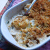 A generous portion of this Perfect Rosemary Gorgonzola Gratin for 2 awaits in a small bowl off to the left of a piping hot casserole dish. Crisp panko and parmesan breadcrumbs top these incredibly creamy gorgonzola scalloped potatoes.