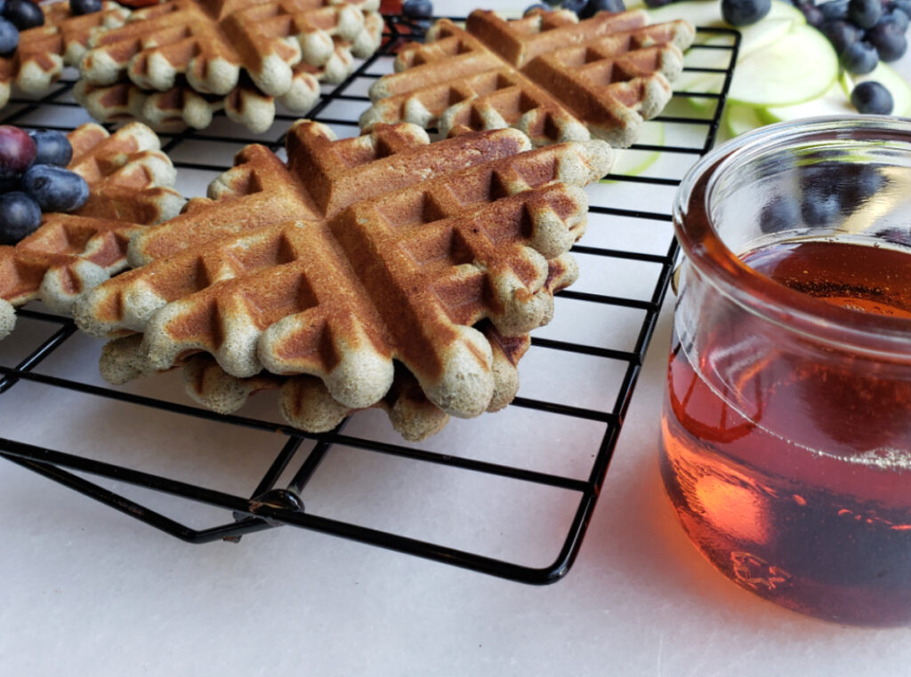 A close up shot of these easy 15-minute blue corn buttermilk waffles with a side of warm maple syrup.