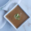 A cup of deliciously creamy Easy 15-minute Thai Peanut Coconut Sauce is topped with fresh, sliced scallions.