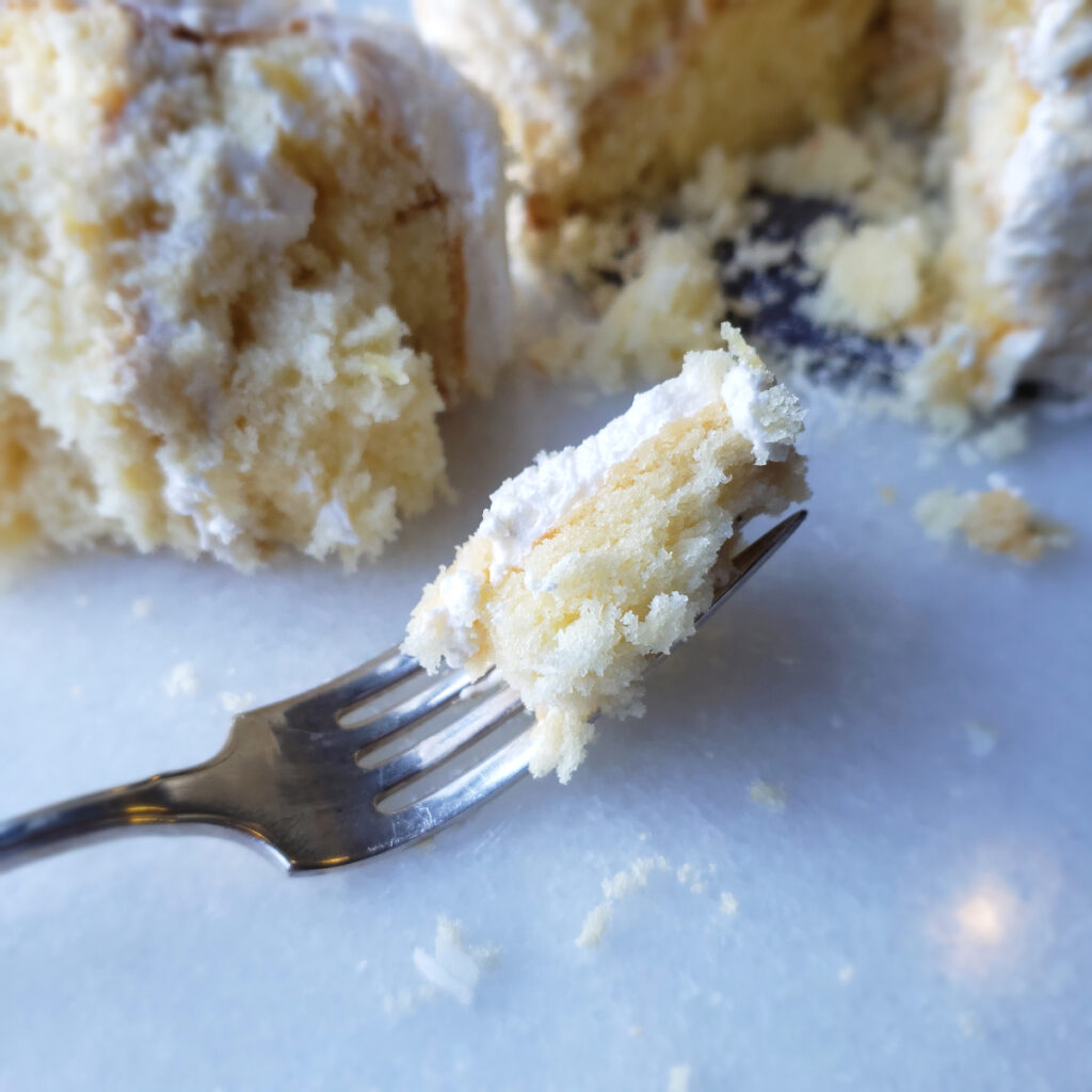Fresh edible flowers and lightly toasted coconut adorn this Easy Pineapple Coconut Cake with 5-Ingredient Rum Buttercream. A perfect bite on a fork reveals this cake's moist, delicate crumb and light buttercream.