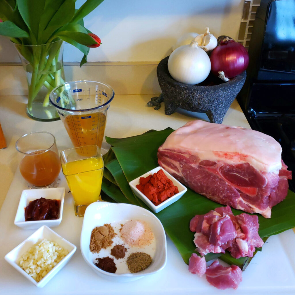 All the ingredients for this Easy Slow Roasted Pork Pibil are displayed on a cutting board.