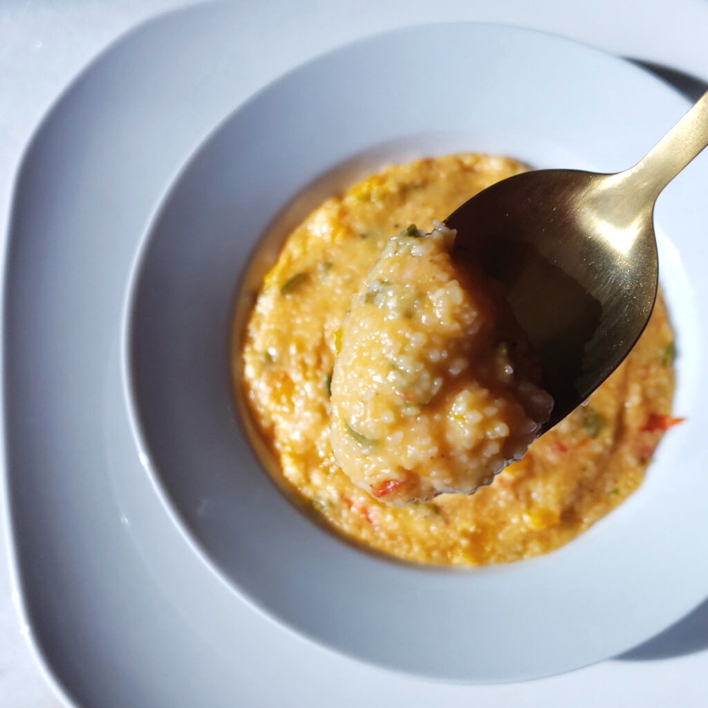 A spoonful of these Easy as 1-2-3 Sofrito Cheese Grits hovers above a generous bowl of these delicious and creamy grits. Pieces of tomato, onion, peppers and garlic shine like gems throughout the mix.