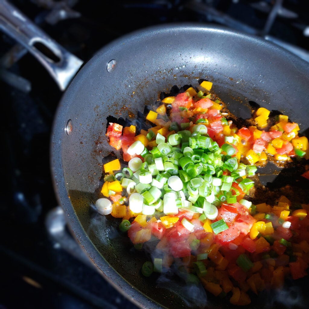 Vegetables prepped for the Sofrito in this Easy as 1-2-3 Sofrito Cheese Grits recipe are in the early stages of being sauteed. The fresh vegetables will cook down to create a flavorful base for these grits.