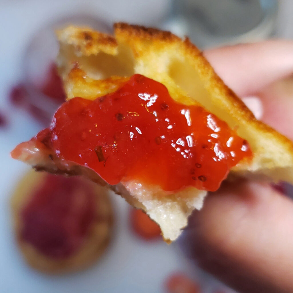 A closeup shot of this A picture of Ball Brand Powdered Pectin is used in this recipe for Easy Strawberry Basil Jam in 15 Minutes on a toasted English Muffin. Pieces of strawberry and minced basil shine through.