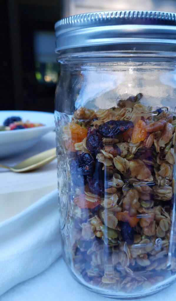 A mason jar is filled with this Crazy Simple 15 Minute Skillet Granola is packed with clusters of dried fruit, toasted oats and nuts, with a hint of cinnamon spice and just the right amount of sweetness from maple syrup.