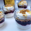 Glass jars of Appalachian Cranachan in 3 Easy Steps feature layers of bourbon and honey-infused whipped cream, fresh berries and toasted honey oats.