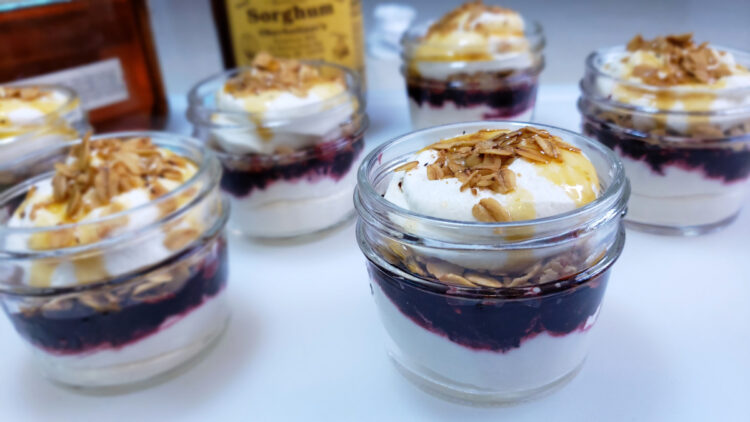 Glass jars of Appalachian Cranachan in 3 Easy Steps feature layers of bourbon and honey-infused whipped cream, fresh berries and toasted honey oats.