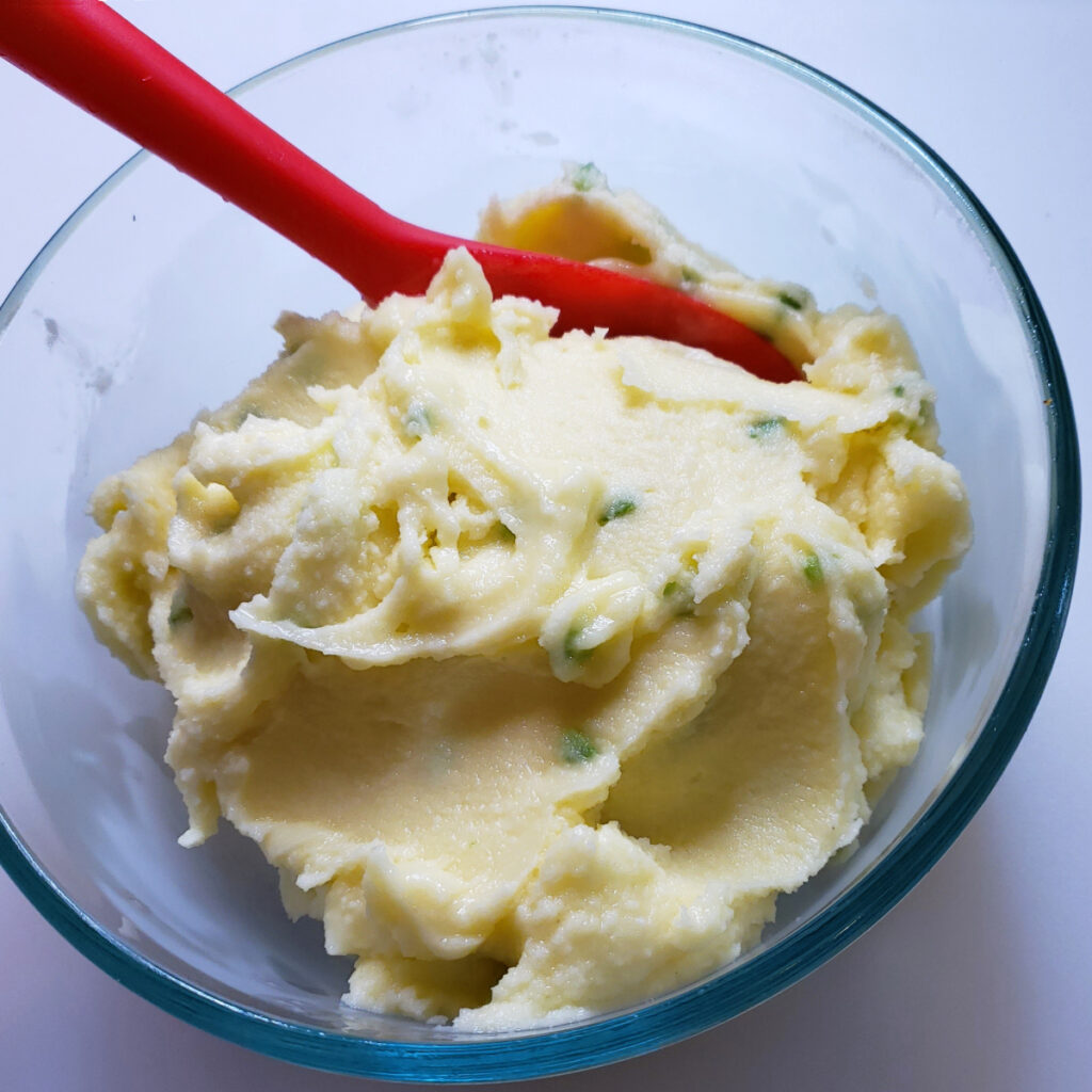 A serving plate with two portions of Easy 5-Ingredient Pineapple Chicharrones Sorbet are topped with crushed chili-flavored cracklings. 