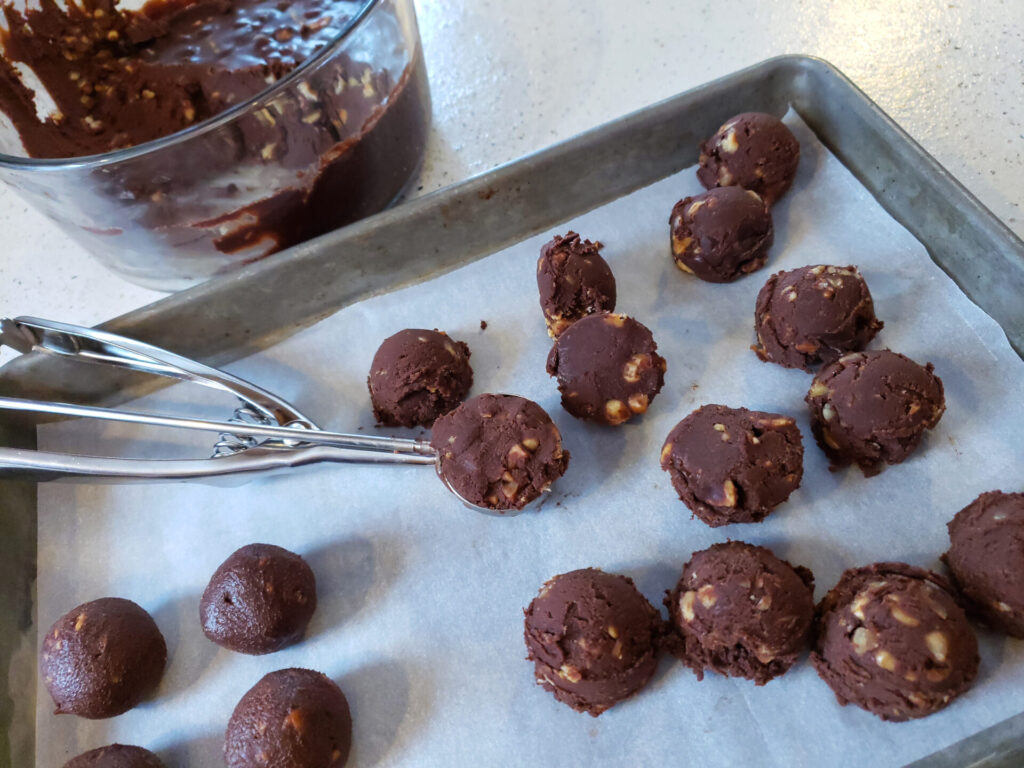 A bowl of chilled ganache used to make these Truly Decadent 5-Ingredient Hazelnut Truffles is scooped and rolled into balls before they are dipped in chocolate. 