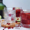 A glass of this Simple 5-Ingredient Rum Pom Punch is served well chilled over ice and topped with a fresh slice of lime and pomegranate arils.