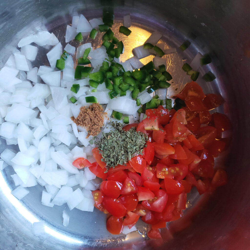 Onions, tomatoes and peppers are sauteed in a pan - the first step to making these Easy Black Beans de la Olla in Under 1 Hour.