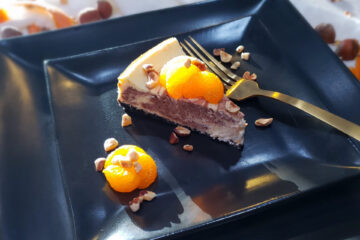 A slice of this Decadent 2 Layer Orange Nutella Cheesecake is topped with fresh oranges and toasted hazelnuts.