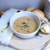 A warm bowl of Creamy Mushroom and Wild Rice Soup in 60 Minutes and a crusty French roll with butter are pictured.