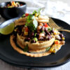 A short stack of these Easy Sweet and Savory Corn Masa Waffles 2 Ways are topped with roasted garden vegetables and garnished with fresh cilantro and a wedge of lime.
