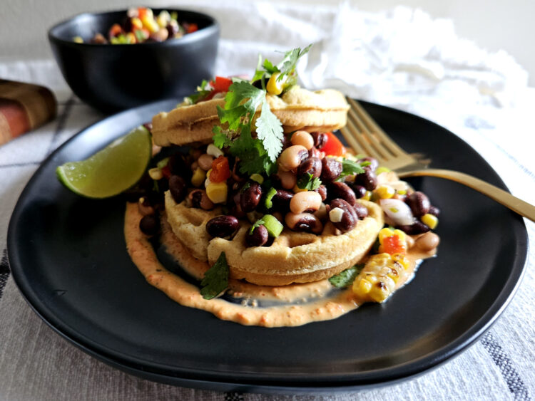 A short stack of these Easy Sweet and Savory Corn Masa Waffles 2 Ways are topped with roasted garden vegetables and garnished with fresh cilantro and a wedge of lime.