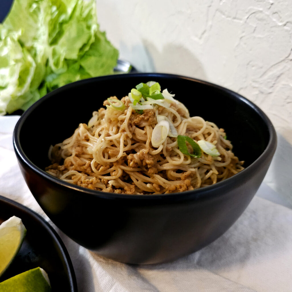 These Easy Dan Dan Noodle Lettuce Wraps in 30 Minutes are prepared with ground chicken and Asian noodles tossed in a sweet and spicy ginger, garlic sauce and wrapped in cool, fresh lettuce leaves. They are then topped with shredded carrot, green onions and peanuts and a generous squirt of fresh lime juice.