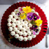A Irresistible Appalachian Buttermilk Velvet Cake 2 Ways sits proudly atop a cake stand. Fresh edible flowers grace the top.