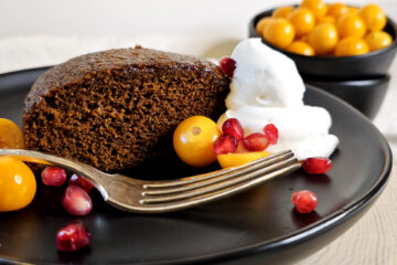 A slice of this moist, tender Festive 5 Star Homemade Gingerbread Cake is served with a dollop of whipped cream, tart gooseberries and pomegranate arils.