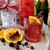 A pitcher of this festive Easy 30 Minute Sparkling Wassail sits neatly on a serving tray with glasses that are garnished with fresh orange slices.