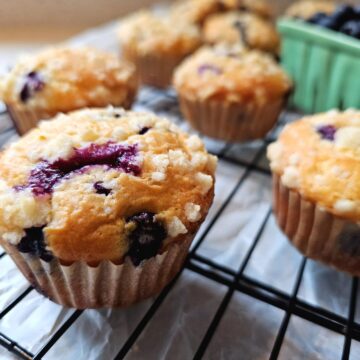 These delightful Lemon Blueberry Muffins sit cooling on a baking rack on the kitchen counter.