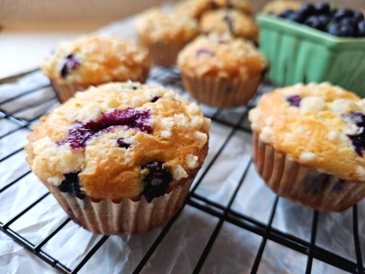 These delightful Lemon Blueberry Muffins sit cooling on a baking rack on the kitchen counter.
