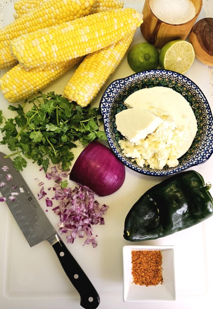 All the ingredients for this Easy Elote Dip Recipe are prepped and ready on a cutting board.