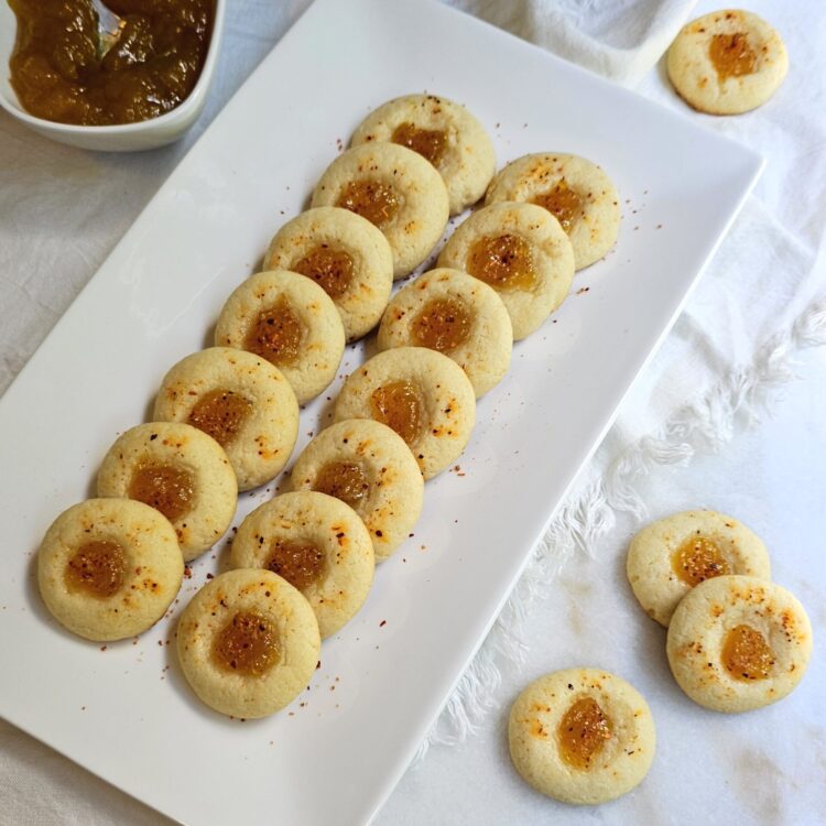 A tray of these Easy 2-Bite Mango Tajín Thumbprints sit in a grouping on a marble board.