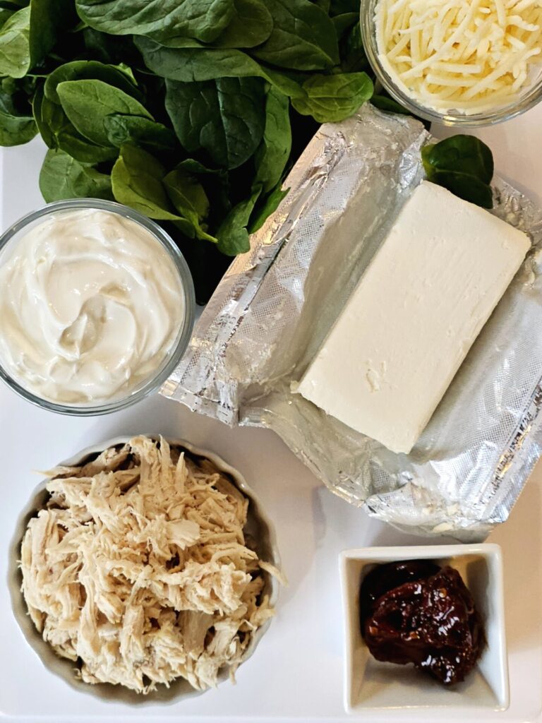 Ingredients to make this Easy Chipotle Chicken Dip in 15 Minutes are displayed on a cutting board.