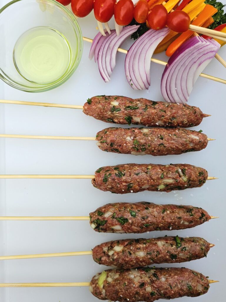 Vegetables and prepared kebabs are ready to be grilled in this Irresistible 30-Minute Lebanese Kafta.
