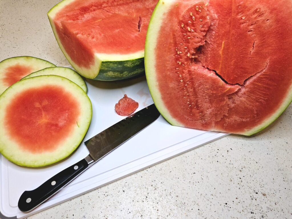 A large watermelon is cut into cubes in preparation for making this watermelon honey recipe.