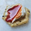 A cracker topped with goat cheese and generous drizzle of watermelon honey.