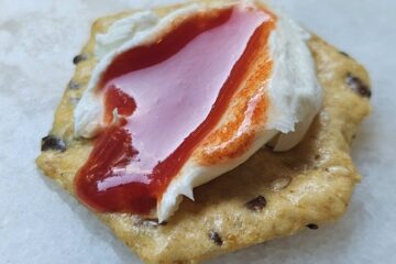 A cracker topped with goat cheese and generous drizzle of watermelon honey.