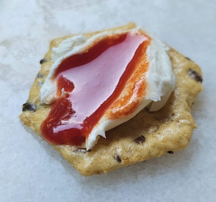 A cracker topped with goat cheese and generous drizzle of watermelon honey.