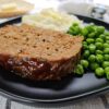 A slice of meatloaf, mashed potatoes, and peas are plated in this Easy Meatloaf Recipe photo.