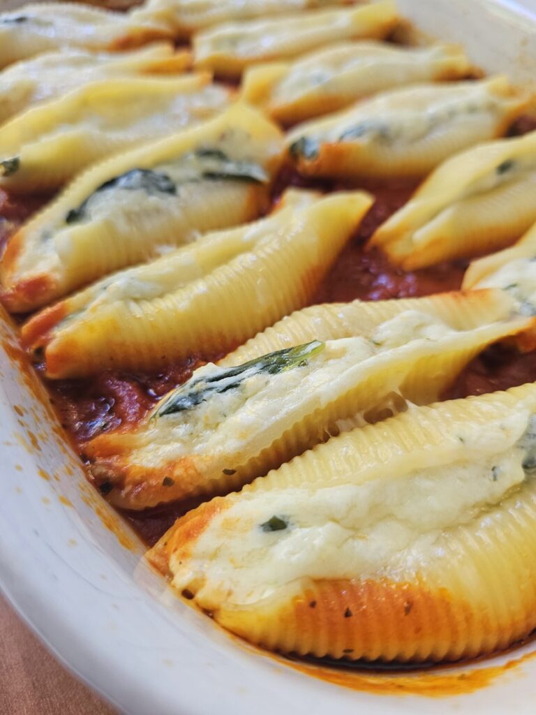 A bubbling hot baking dish of Authentic Italian Stuffed Shells in 1 Hour sits cooling on the kitchen counter.